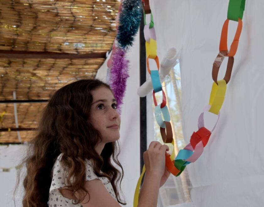 Girl hanging a paper chain in a succah